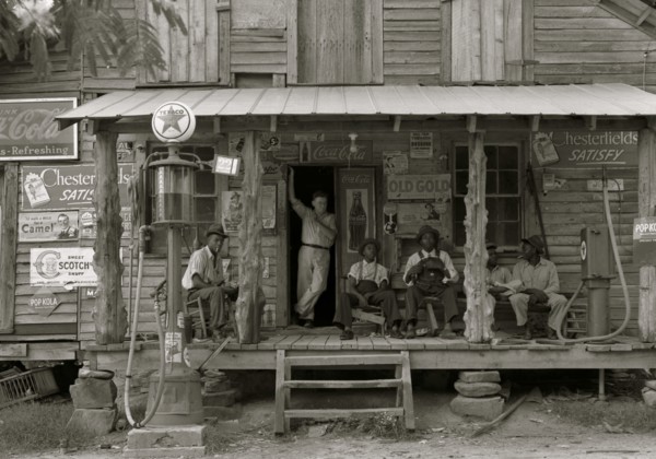 African American and a white store owner on the Porch of a country store 1939