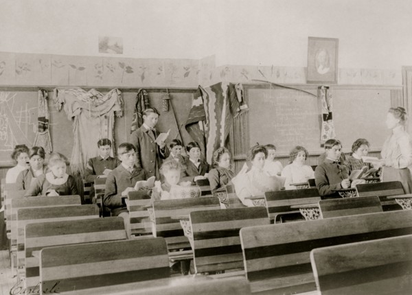 Classroom at the Indian Industrial School, Carlisle, Pennsylvania, showing teacher observing students reading. 1901
