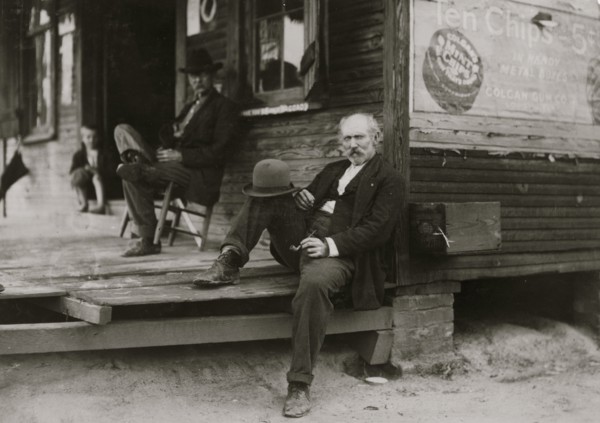 Dependent Widower sits on steps; the children work to support him 1911
