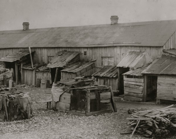 Father taking it easy at home while his two girls work in the cotton mill. 1911