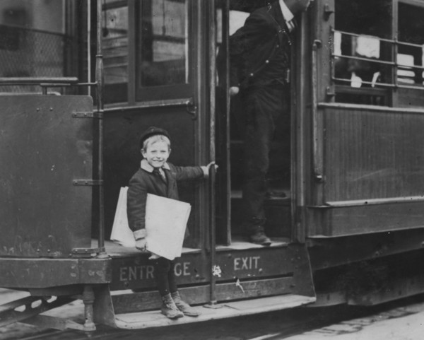 Francis Lance, 5 years old, 41 inches high. Sells regularly on Grand Avenue. He jumps on and off moving cars at risk of life. 1910