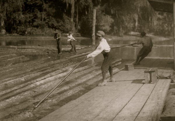 Hard work and dangerous. This "river-boy" Lyman Frugia. Poles the heavy logs into the incline that takes them up to the mill.  1914