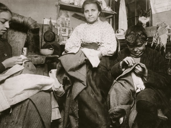 High up on the top floor of a rickety tenements, immigrants, this mother and her two children were living in a tiny one room, and were finishing garments.  1924