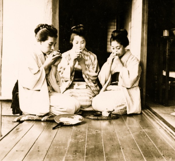 Japanese women seated on floor sipping tea. 1901