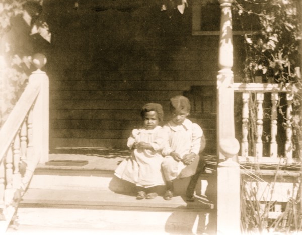 Two African American children sitting on steps to porch 1899