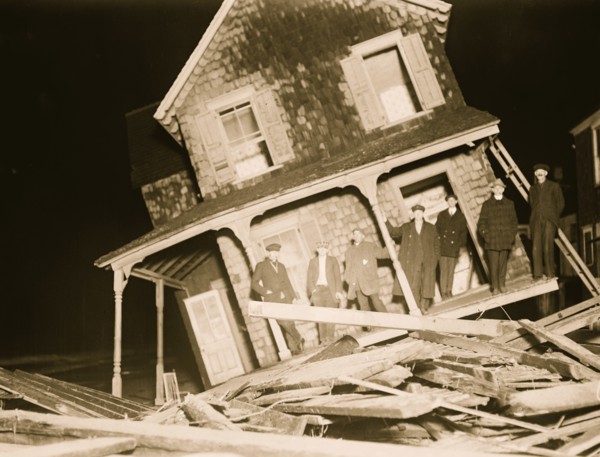 Wrecked Cottage at Seabright with men on tilted front Porch