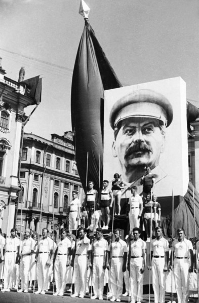 Participants in the annual physiacal culture parade standing under a portrait of joseph stalin near red square in moscow, ussr, 1930s.
