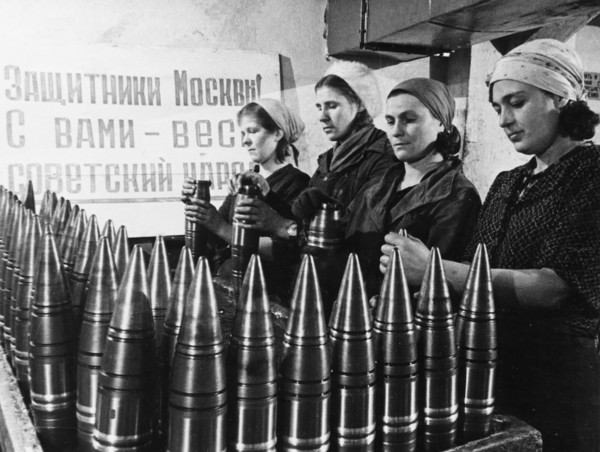 Civilian women making artillery shells at a munitions factory in moscow during world war 2, the sign behind them reads: 'defenders of moscow! the soviet people are with you!'.