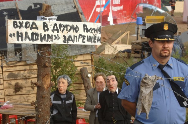 Sign reading 'entrance to the other russia for our people forbidden', a security guard and a puppet of tycoon boris berezovsky, third from left, seen at the summer camp of the pro-putin nashi (our peo...