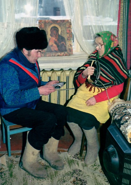 Petrozavodsk, russia, january, 16 2003: 86-year-old yevdokiya obukhovskaya (right) and her son-in-law ivan pukroyev trying to get some warmth from an iron, central steam heating and gas supply have no...