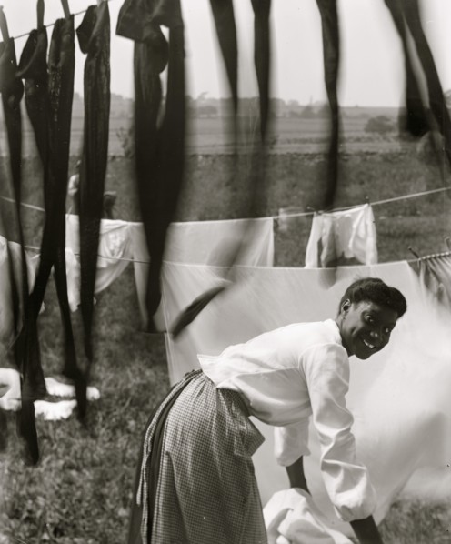 Black and white, an informal portrait of a young Negro woman surrounded by laundry in Newport, R.I.