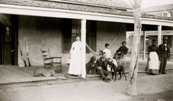 Two soldiers and two women on porch, with Afro-American woman and man to right, Fort Verde, Arizona