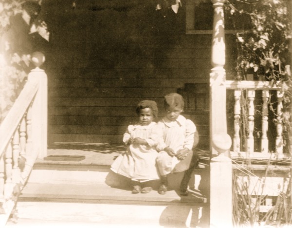 Two African American children sitting on steps to porch