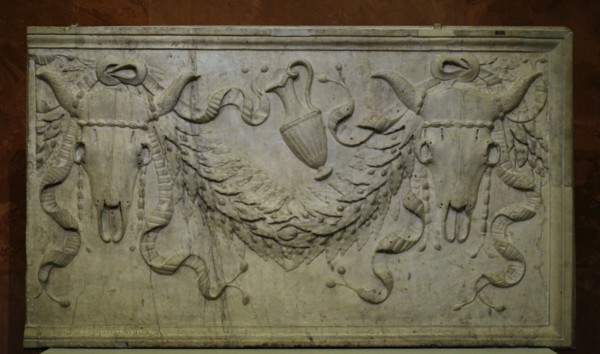 Sacrifical bull's skulls, vase and garlands.