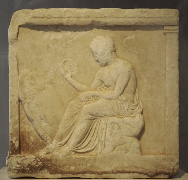 Base of a statue with reliefs. Boy seated, holding a crown in his hand.