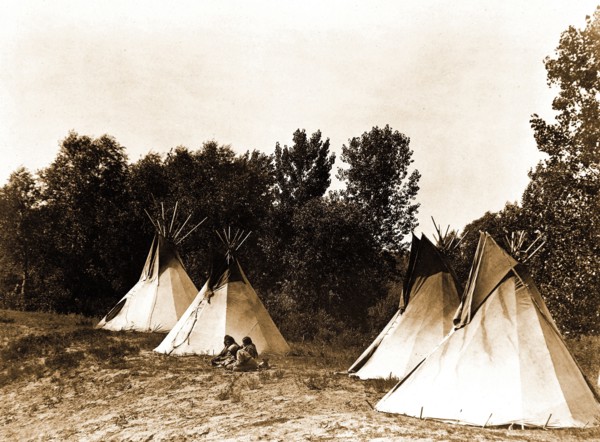 Edward S. Curtis Native American Indians - An Assiniboin camp containing four tepees with Indians seated on ground circa 1908.