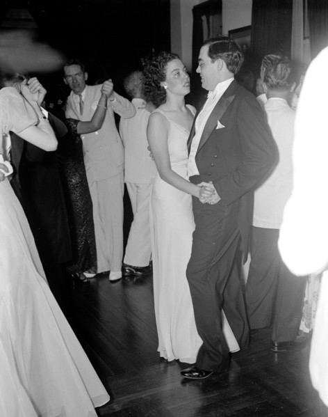 A happy couple dancing at a reception circa 1937 .