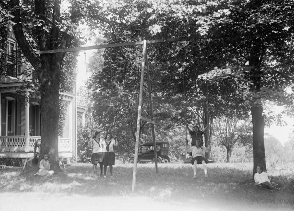 Children having fun and playing on a swing set at a YWCA camp circa 1919 .