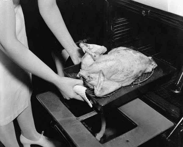 A woman demonstrates how to correctly cook a turkey circa 1937.