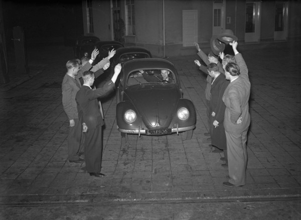 Men wave hello to the 'first volkswagen' (original caption) circa October 16, 1947.