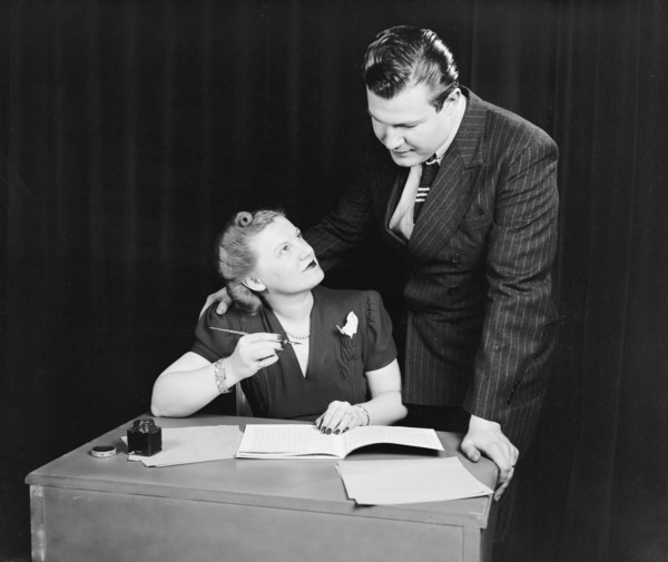 Staged photo of a man and woman (possibly married couple) working on a monthly budget circa 1940 .