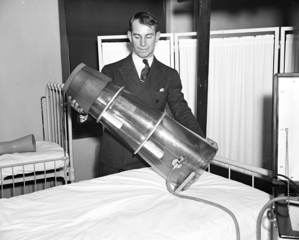 Leg saver. Chester Antos, student at Georgetown University medical school, photographed with the newly devised Emerson suction pressure apparatus which designers believe will prevent amputation in man...