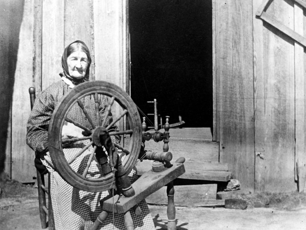 Mountain woman sitting behind her spinning wheel