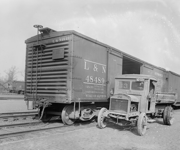 Truck parked next to an empty railroad car (box car) ca.  between 1910 and 1926