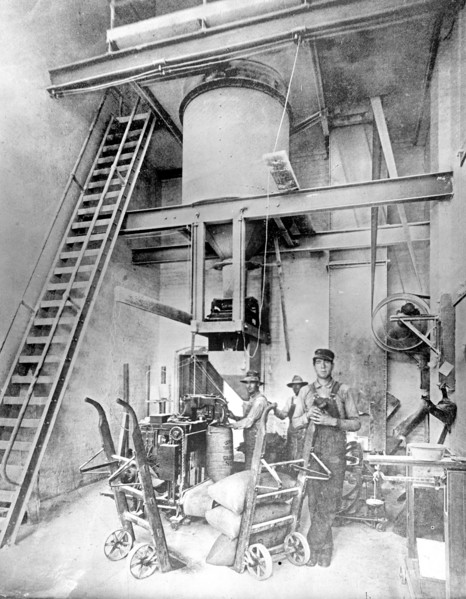 Workers filling, weighing, and sewing sacks of granulated sugar in a beet sugar factory ca.  between 1910 and 1920