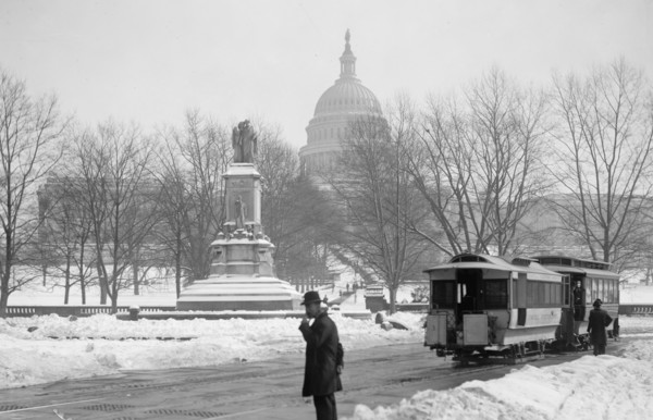 Man standing near the U.S. Capitol on a snowy day ca. between 1909 and 1923