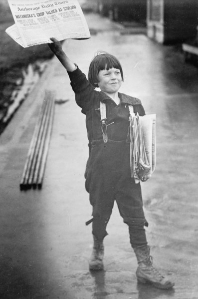 Young newsboy in Alaska selling newspapers ca. between 1909 and 1920