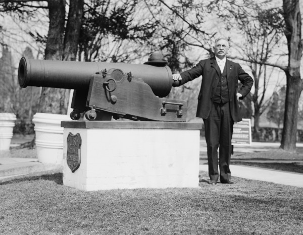 J.F. Schnell, Superintendent of  Battle Cemetery standing next to a cannon ca. between 1909 and 1919