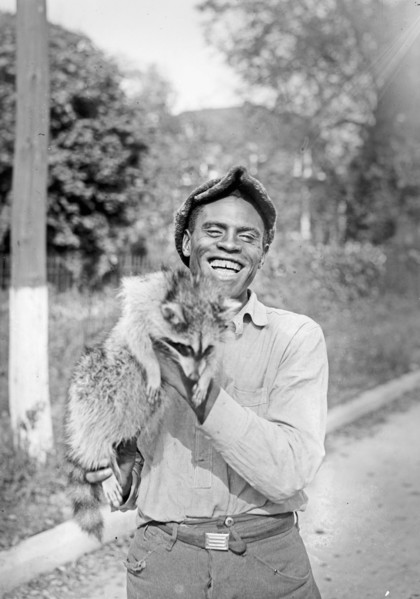 Smiling man holding a racoon  ca.  between 1918 and 1921