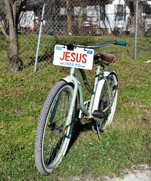 A bicycle with a JESUS license plate sitting in the front yard of a home in a small Texas town