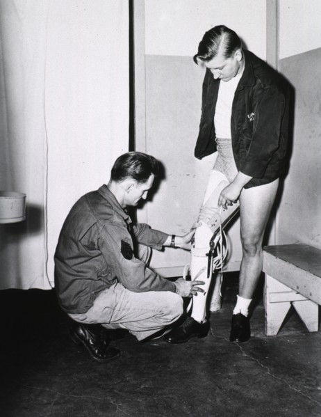 A young man being fitted with a prosthetic leg ca. mid