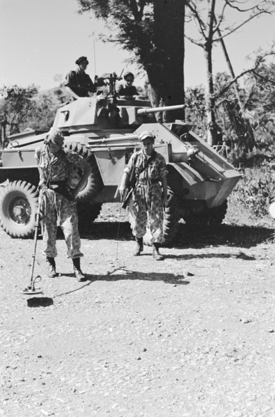 Soldier with a metal detector in search of land mines. Behind him a Humber armored car; Date June 1947; Location Indonesia, Dutch East Indies