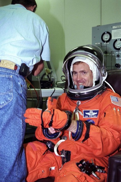 STS-94 Mission Commander James D. Halsell, Jr., puts his left glove on while he is assisted into his launch/entry suit in the Operations and Checkout (O&C) Building
