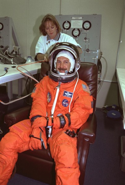 STS-85 Commander Curtis L. Brown, Jr. smiles as he is assisted with his ascent/reentry flight suit by a suit technician in the Operations and Checkout (O&C) Building ca. 1997