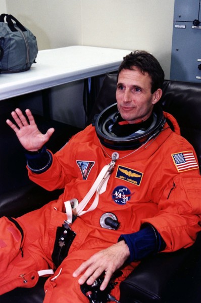 1997 - STS-81 Mission Specialist Jerry Linenger waves to the camera in his launch/entry suit and helmet in the suitup room of the Operations and Checkout (O&C) Building.