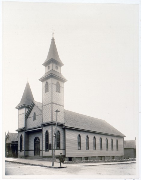 African American man standing on sidewalk in front of church c. 1900