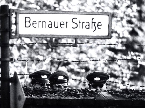 Three Communist 'VOLPO's', East German Police, Stretch to Get a Look Over a Cemetery Wall Which