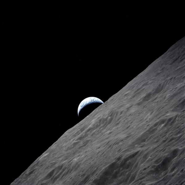 The crescent Earth rises above the lunar horizon