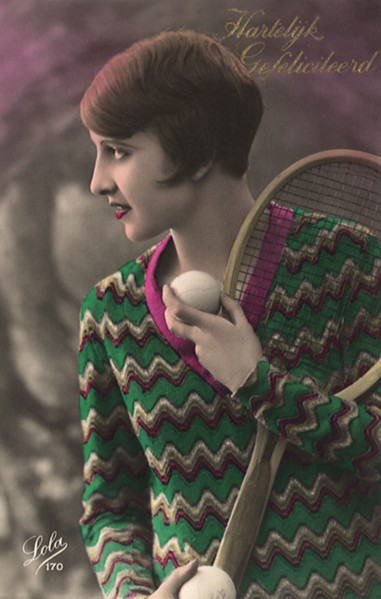 Woman with short hair & sweater with tennis racquet and ball.