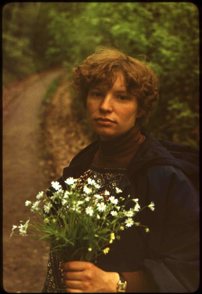 Young caucasian woman with a bouquet of daisies on a background of the road, turning to the forest.