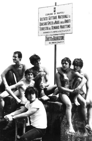 Young man at naples's harbour, no swimming sign, 70's