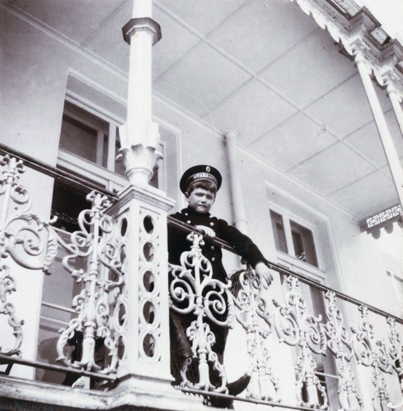 Tsarevich Alexei Nikolaievich of Russia stands on the banister of Alexander Palace's Balcony