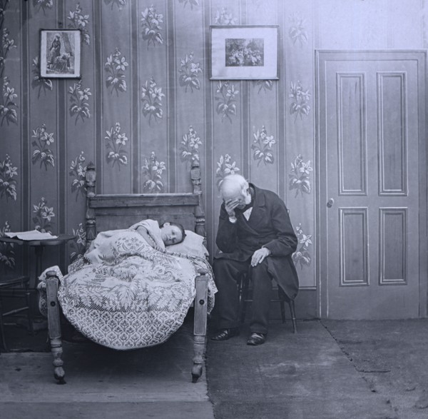 Jessica lies ill on bed with a vicar sitting next to her.