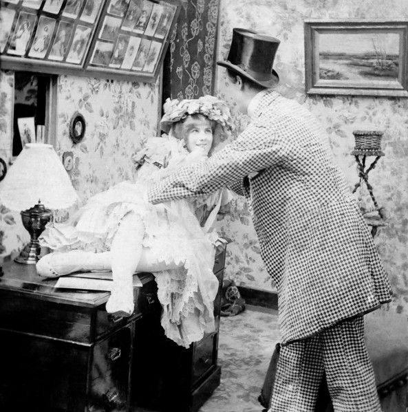 Lady on desk with man holding her.