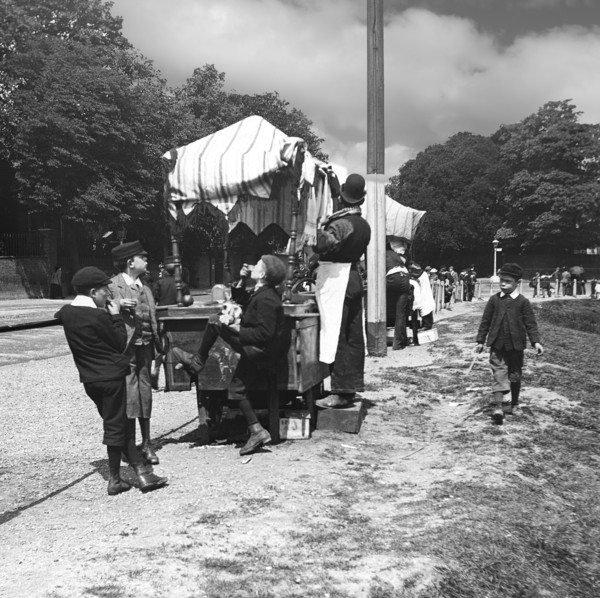 A view of children and people at a market in the park, perhaps an exhibition.