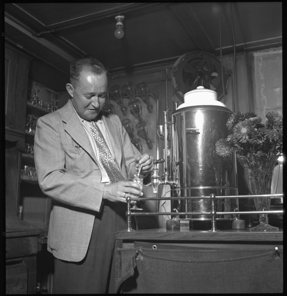 Heinz Ambuehl serving schnapps at his restaurant; Zell ca. 1948 .